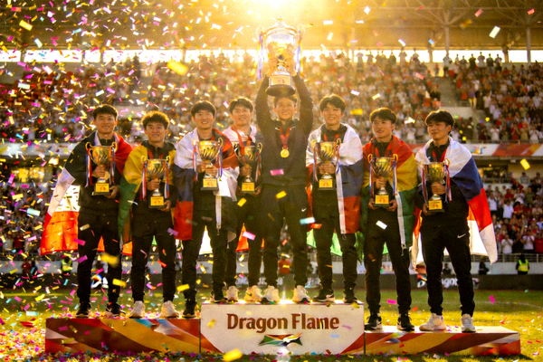 Dragon Flame全队站在领奖台上，手捧冠军奖杯，身披国旗，彩带从空中飘落