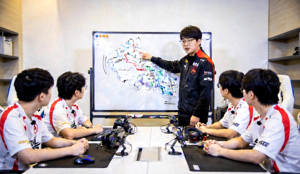 电竞教练在战术板前为选手讲解亚运新规则 - 白板上画有地图路线